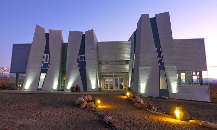 The angular white building of the Glaciarium ice museum in El Calafate, lit up at dusk