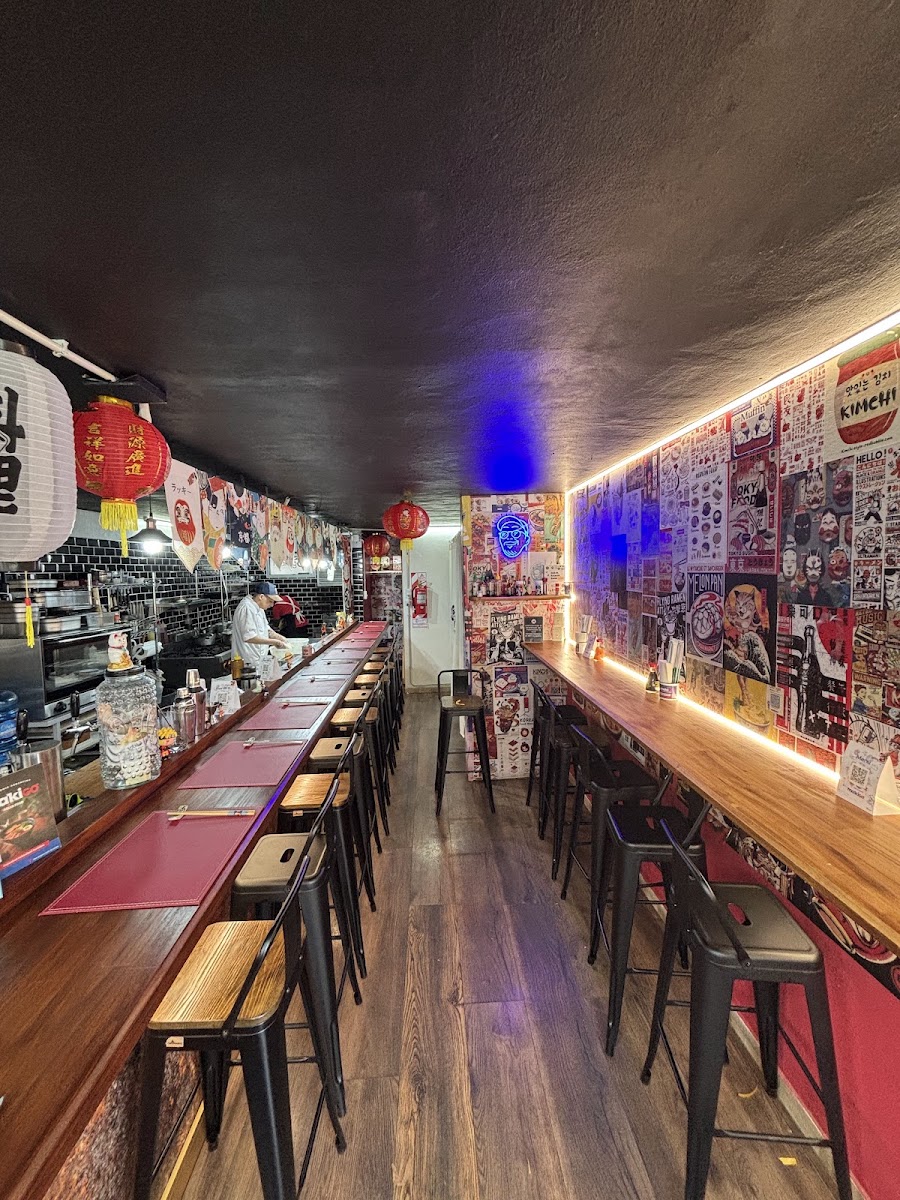 Inside Maki Go in El Calafate: a long counter with stools, red lanterns and walls covered in posters